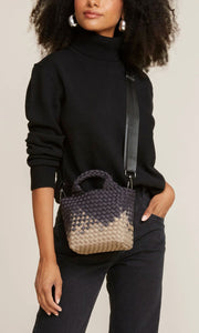 Woman standing with Naghedi handwoven neoprene St. Barths Petit Tote bag in Graphic Ombre Mahal, available at Amara Home.